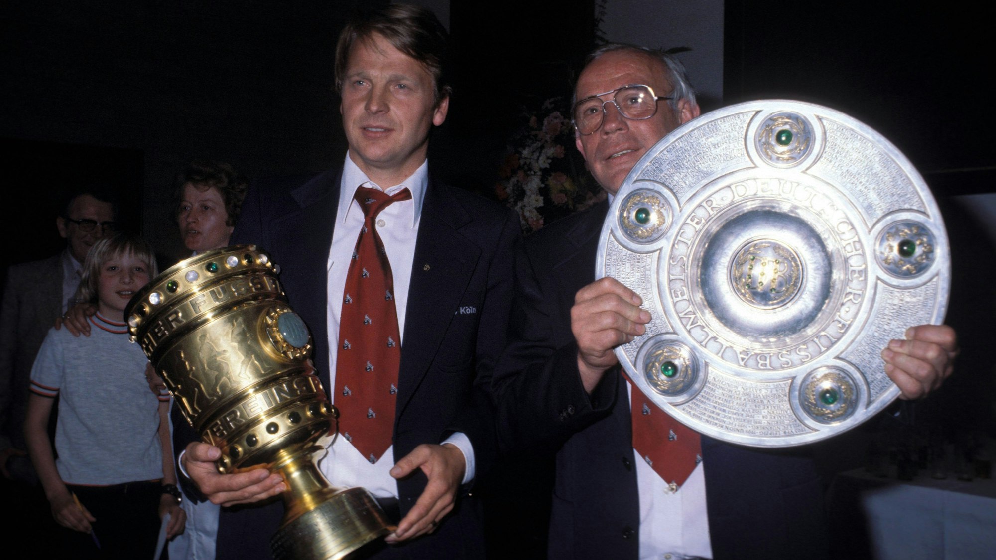Manager Karl-Heinz Thielen und Trainer Hennes Weisweiler präsentieren beim 1. FC Köln den DFB-Pokal und die Meisterschale.