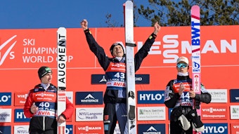 Daniel Tschofenig, Andreas Wellinger und Ryoyu Kobayashi auf dem Siegerpodest in Lake Placid. Wellinger reißt jubelnd die Arme hoch.