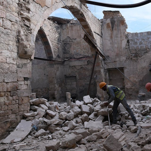 Bauarbeiter stehen beim Wiederaufbau des Khabiya Markts im historischen Viertel Souk der Altstadt von Aleppo zwischen Trümmern eines zerstörten Gebäudes. (2019)