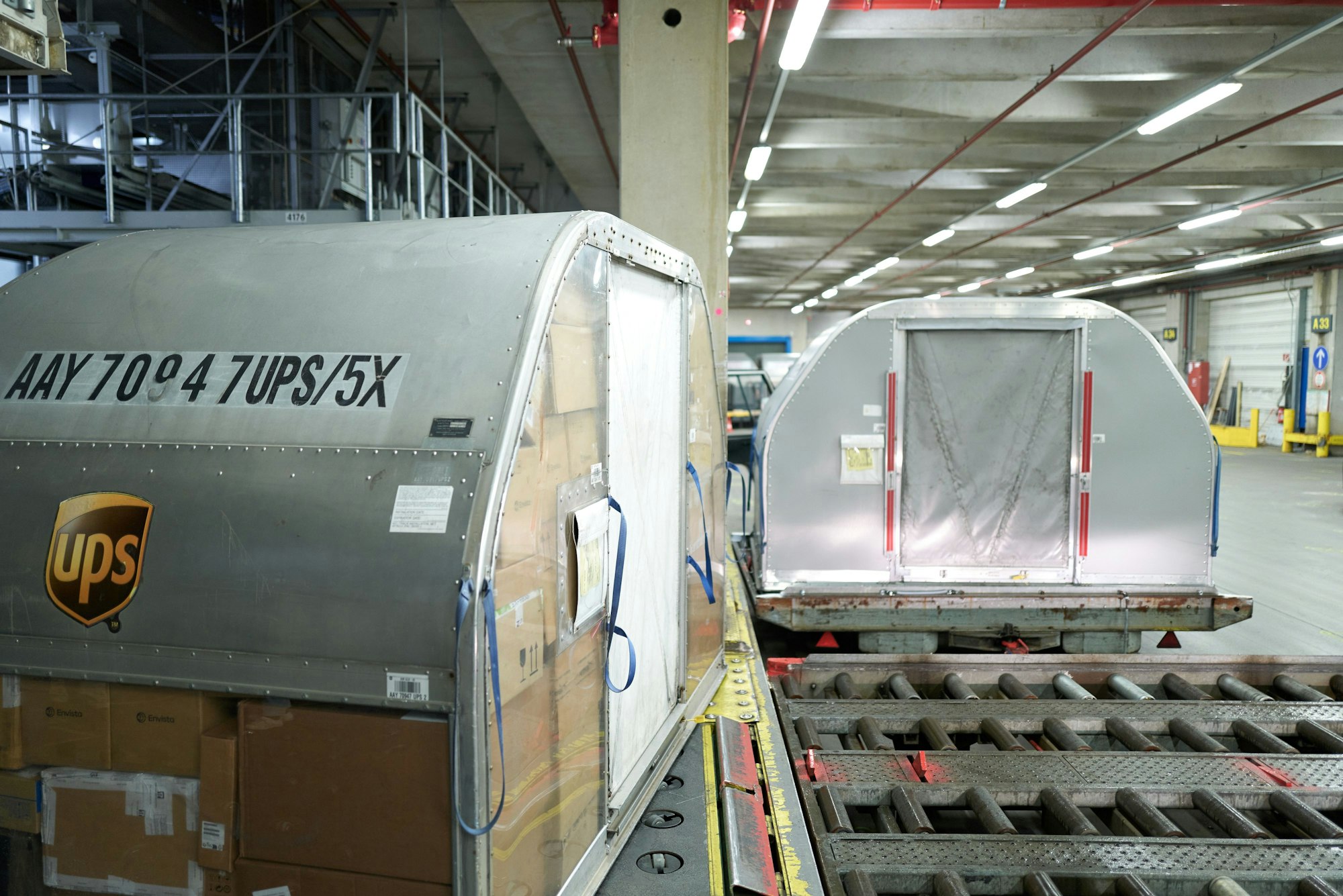 Flugcontainer werden auf Transporter verladen, die sie zu den Flugzeugen fahren.