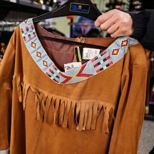 Ein Mann hält ein Kostüm zur Verkleidung als Indianer in der Hand.