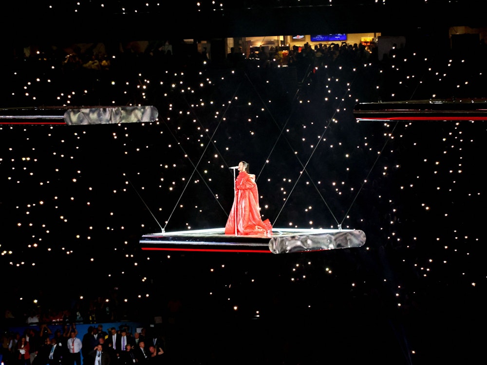 Rihanna singt einen Song auf einer freischwebenden Plattform. Auf den Zuschauerrängen leuchten zahlreiche Handykameras.