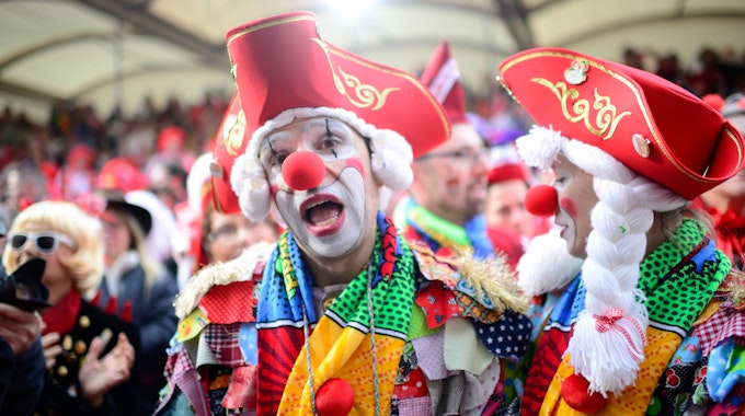 Ein als Clown verkleideter Mann mit roter Pappnase und rotem Hut steht vor der Tribüne am Alter Markt an Weiberfastnacht 2020.
