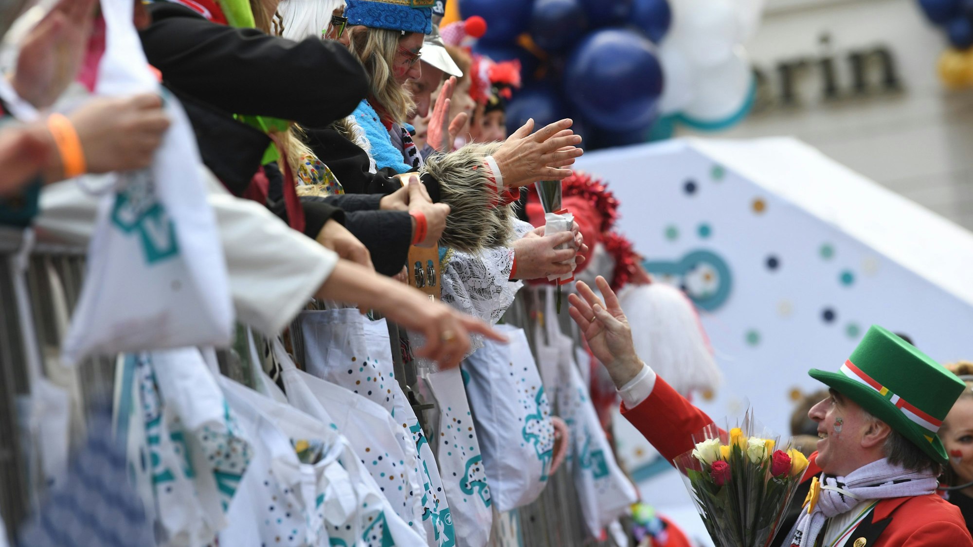 Karnevalisten auf dem Wagen verteilen Kamelle und Blumensträuße (Strüßjer) beim Rosenmontagszug.
