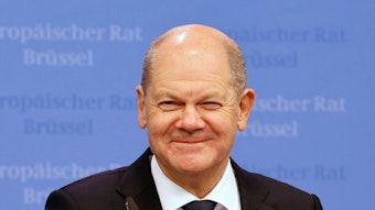 Bundeskanzler Olaf Scholz (SPD) grinst bei einer Pressekonferenz in Brüssel in die Kamera.