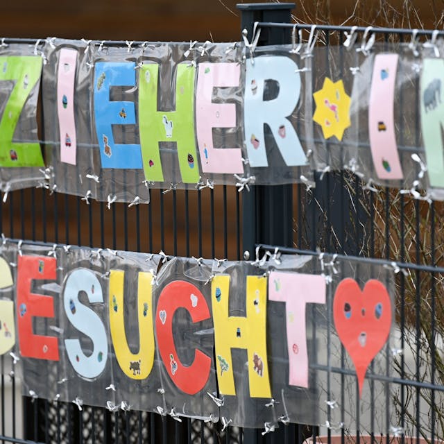 Mit bunten Buchstaben sind die Worte "Erzieher*in gesucht" geschrieben, die an einem Zaun einer Kindertagesstätte befestigt sind.&nbsp;