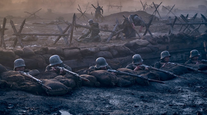 Eine Filmszene: Soldaten liegen mit angelegten Gewehren in einem Schützengraben.