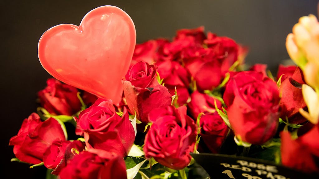 Ein rotes Herz in einem Strauß roter Rosen.