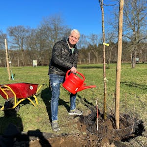Guido Cantz gießt einen Apfelbaum der Sorte Schick's Rheinischer Landapfel auf der Obstwiese auf Gut Leidenhausen im Kölner Stadtteil Porz-Eil.