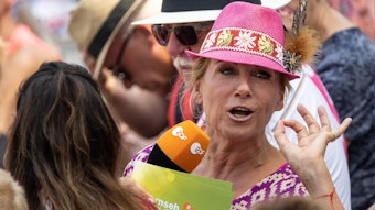 Andrea Kiewel, hier im „Fernsehgarten“, trägt einen rosa Hut auf dem Kopf.