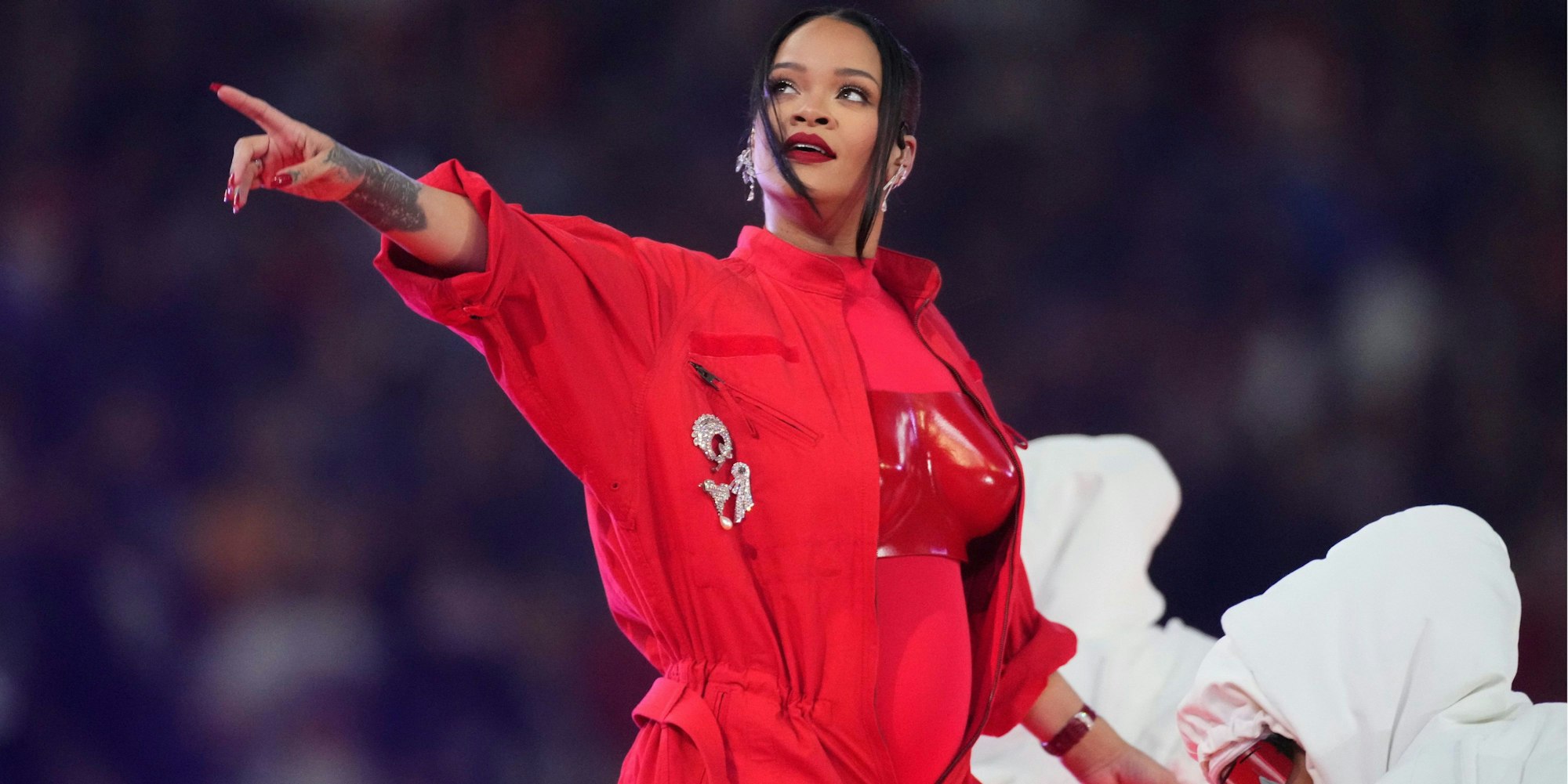Rihanna tritt während der Halbzeitshow des Super Bowl im State Farm Stadium in Glendale, Arizona auf. Sie trägt einen hellroten Anzug mit dunkelroter Brustplatte.