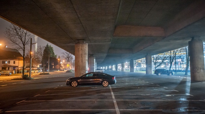 Nachtaufnahme unter der Stelzenautobahn. Ein einzelnes Auto steht auf dem Parkplatz unter der Stelze.