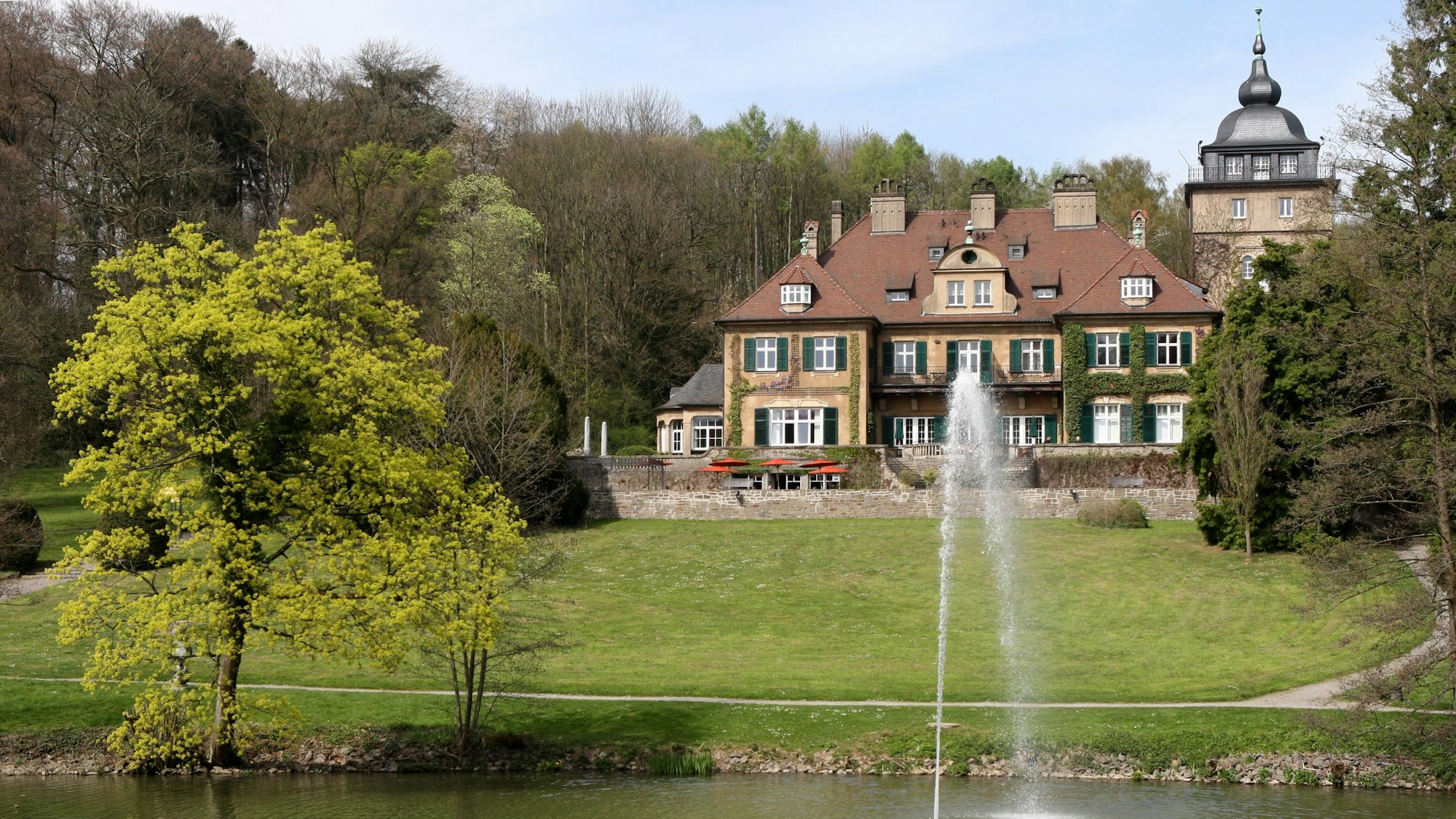Schloss Lerbach mit Grünanlage und Teich davor.