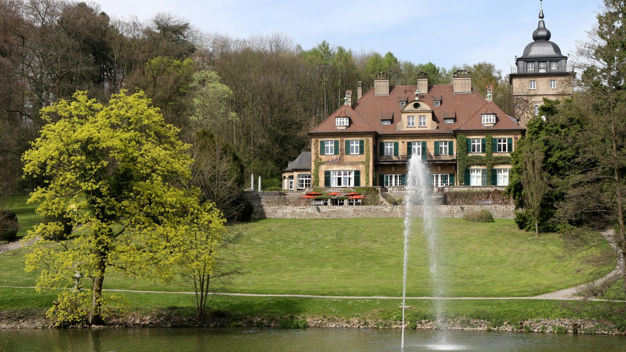 Schloss Lerbach mit Grünanlage und Gewässer davor.