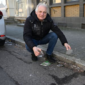 Bernd Trauschies kniet am Straßenrand vor herumliegendem Müll.