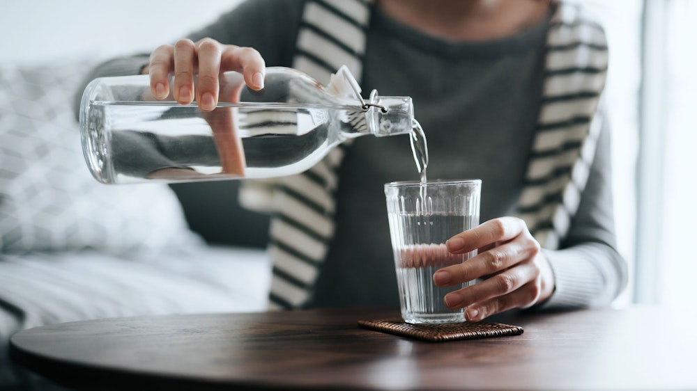 Eine Frau gießt sich ein Glas Wasser ein.