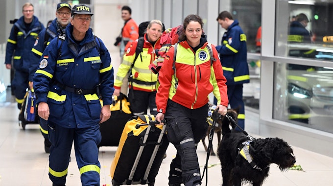 Rettungskräfte werden von jubelnden Menschen auf dem Flughafen in Köln begrüßt.
