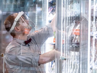 Ein Mitarbeiter einer Supermarktkette sortiert Waren in ein Kühlregal.