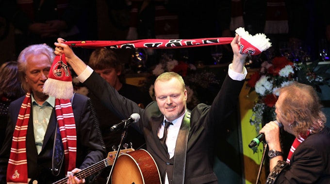 Stefan Raab singt mit der Band Höhner und hält einen FC-Schal hoch.