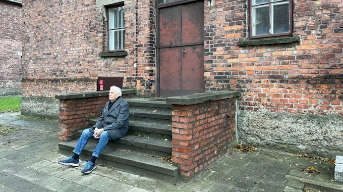 Dany Dattel sitzt auf der Treppe vor Block 10 im Stammlager Auschwitz.