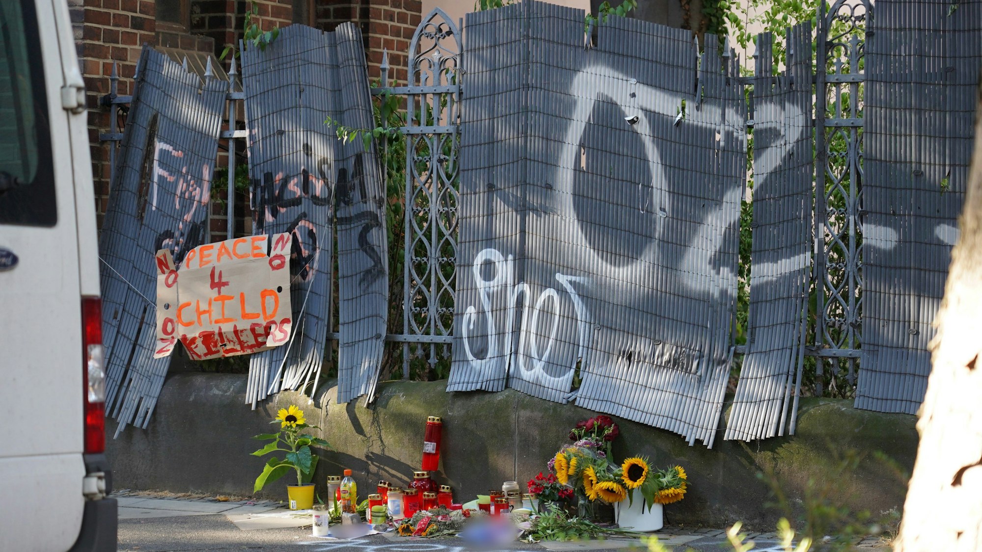 An einem Zaun sind Kerzen und Blumen abgelegt worden, mit denen eines von der Polizei erschossenen Jugendlichen gedacht wird.