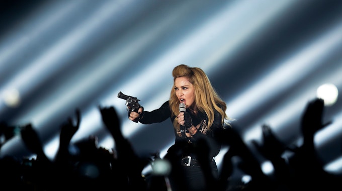 Die US-amerikanische Sängerin Madonna steht in der Lanxess-Arena in Köln mit einer Waffe auf der Bühne.