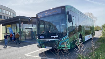 Ein grüner Wupsi-Bus steht an einer Haltestelle.