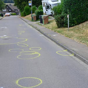 Auf einer Straße sind zahlreiche gelbe Markierungen der Polizei zu sehen.