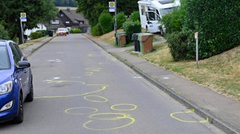 Auf einer Straße sind zahlreiche gelbe Markierungen der Polizei zu sehen.