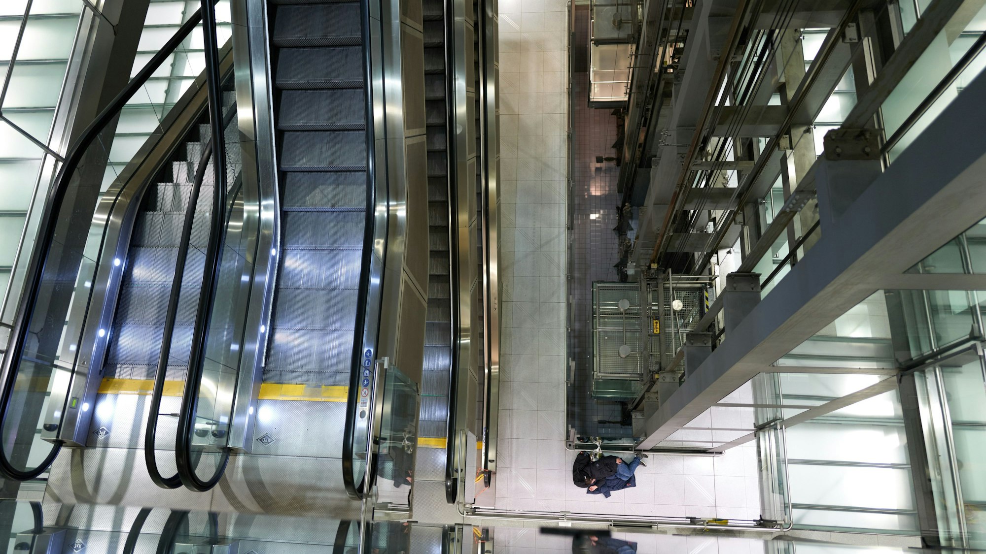 09.02.2023, Flughafen Köln-Bonn: Wir dokumentieren, was nachts auf dem Flughafen passiert. Die verschiedenen Ebenen von innen fotografiert im Terminal 2. Unten schläft ein Reisender neben dem Aufzug.