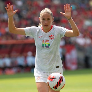 Fußballerin Janine Beckie (Kanada) hebt auf dem Spielfeld die Hände hoch.