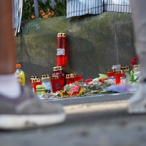 Zwei Menschen stehen vor einem Zaun, an dem mit Kerzen und Blumen eines von der Polizei erschossenen Jugendlichen gedacht wird. Im Fall um tödliche Polizeischüsse in Dortmund hat die Staatsanwaltschaft Anklage gegen fünf Polizisten erhoben.