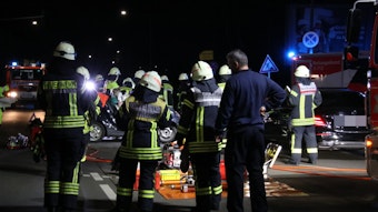 Einsatzkräfte der Feuerwehr stehen an der Unfallstelle im Kreuzungsbereich Friedrich-Karl-Straße und Niehler Kirchweg in Köln-Weidenpesch.