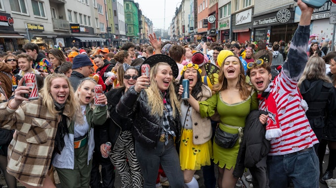 Eine Gruppe kostümierter Menschen feiert Karneval auf der Zülpicher Straße und lacht in die Kamera