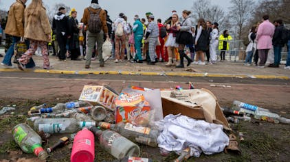 Das Foto zeigt leere Glasflaschen und Müll auf einer Wiese.