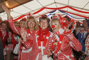 Drei kostümierte Frauen stehen nebeneinander im Festzelt, sie tragen Bekleidung in roten und weißen Farben.