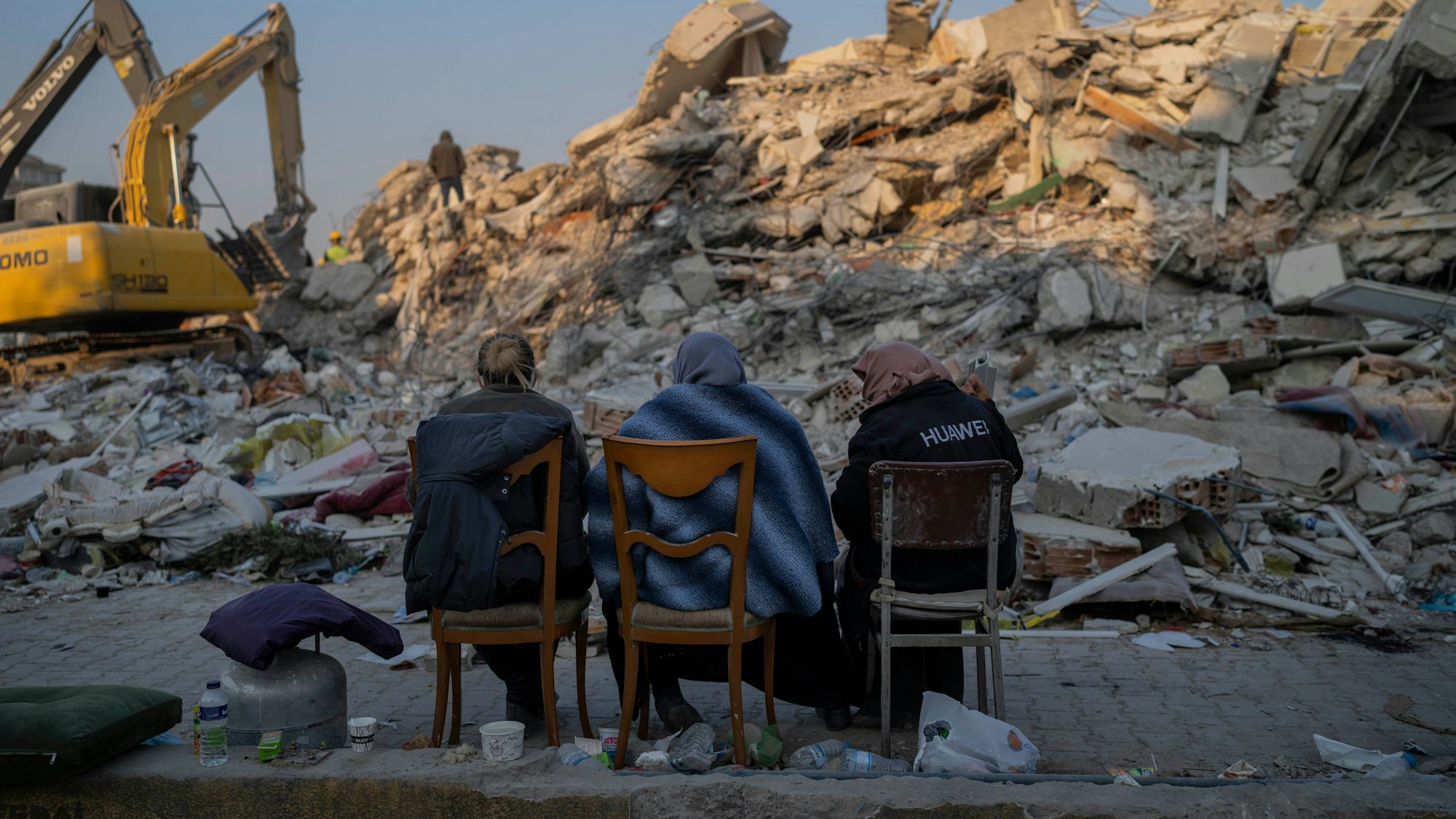 Türkei, Antakya: Frauen sitzen vor den Trümmern bei dem Erdbeben zerstörter Gebäude. Auch rund eineinhalb Wochen nach der Erdbebenkatastrophe mit Zehntausenden Toten erschüttern immer noch weitere Erdstöße die Katastrophenregion.