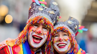 Karnevalisten feiern an Weiberfastnacht die Eröffnung des Straßenkarnevals auf dem Alter Markt in Köln. Sie sind bunt verkleidet und geschminkt.
