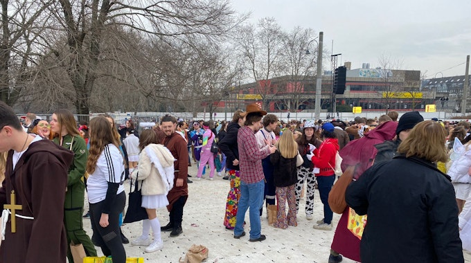 Menschen feiern Karneval auf den abgedeckten Uniwiesen.