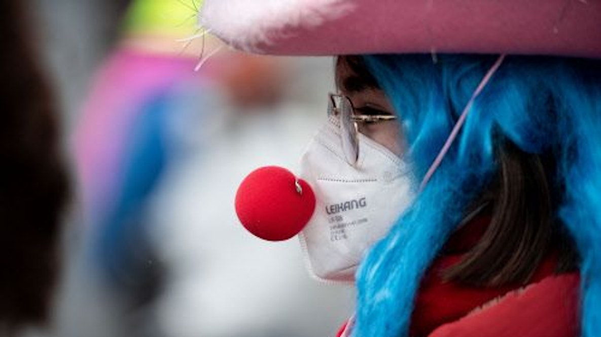 Eine verkleidete Frau trägt eine Clownsnase über einer FFP2 Maske.