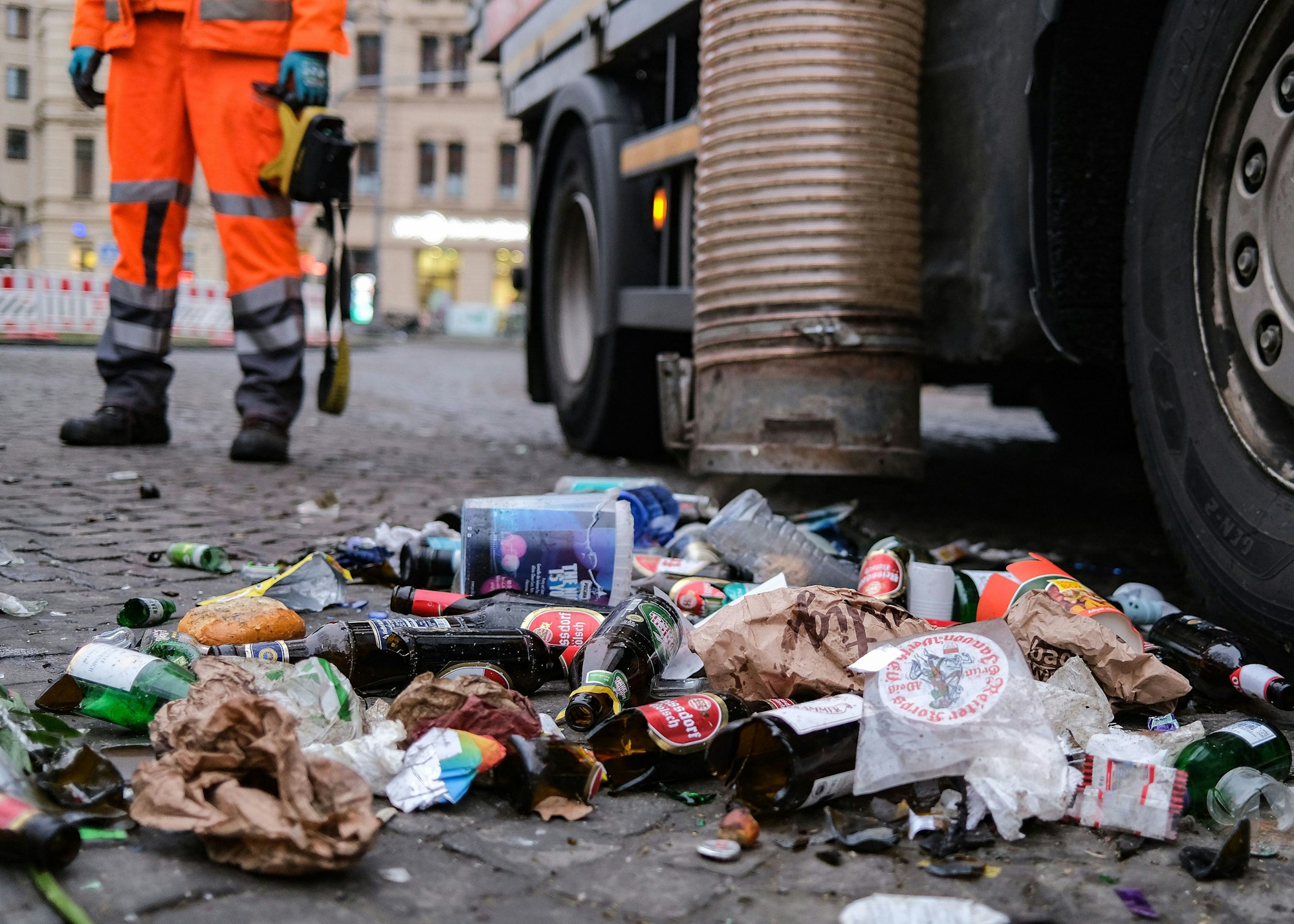 17.02.2023, Nordrhein-Westfalen, Köln: Zusammengefegter Müll aus der Weiberfastnacht wird von der Straßenreinigung aufgesaugt. Mit der Weiberfastnacht hat der traditionelle Straßenkarneval begonnen. Foto: Oliver Berg/dpa +++ dpa-Bildfunk +++