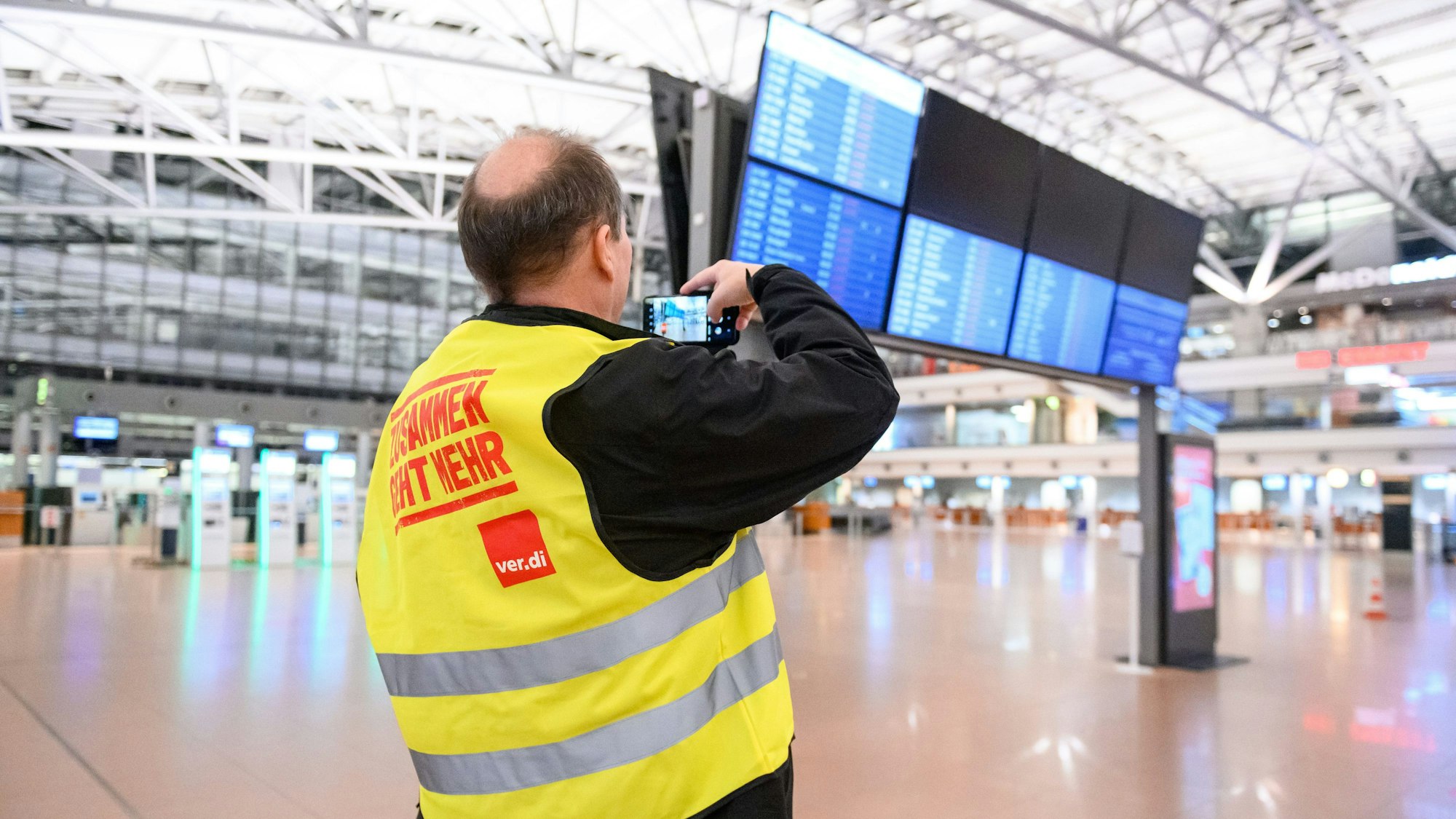 Ein Flughafen-Mitarbeiter steht mit Streikweste im sonst menschenleeren Terminal 1 am Hamburger Flughafen