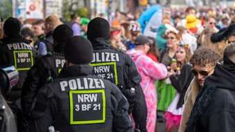 Polizeibeamte stehen inmitten von Feiernden auf einer Straße.