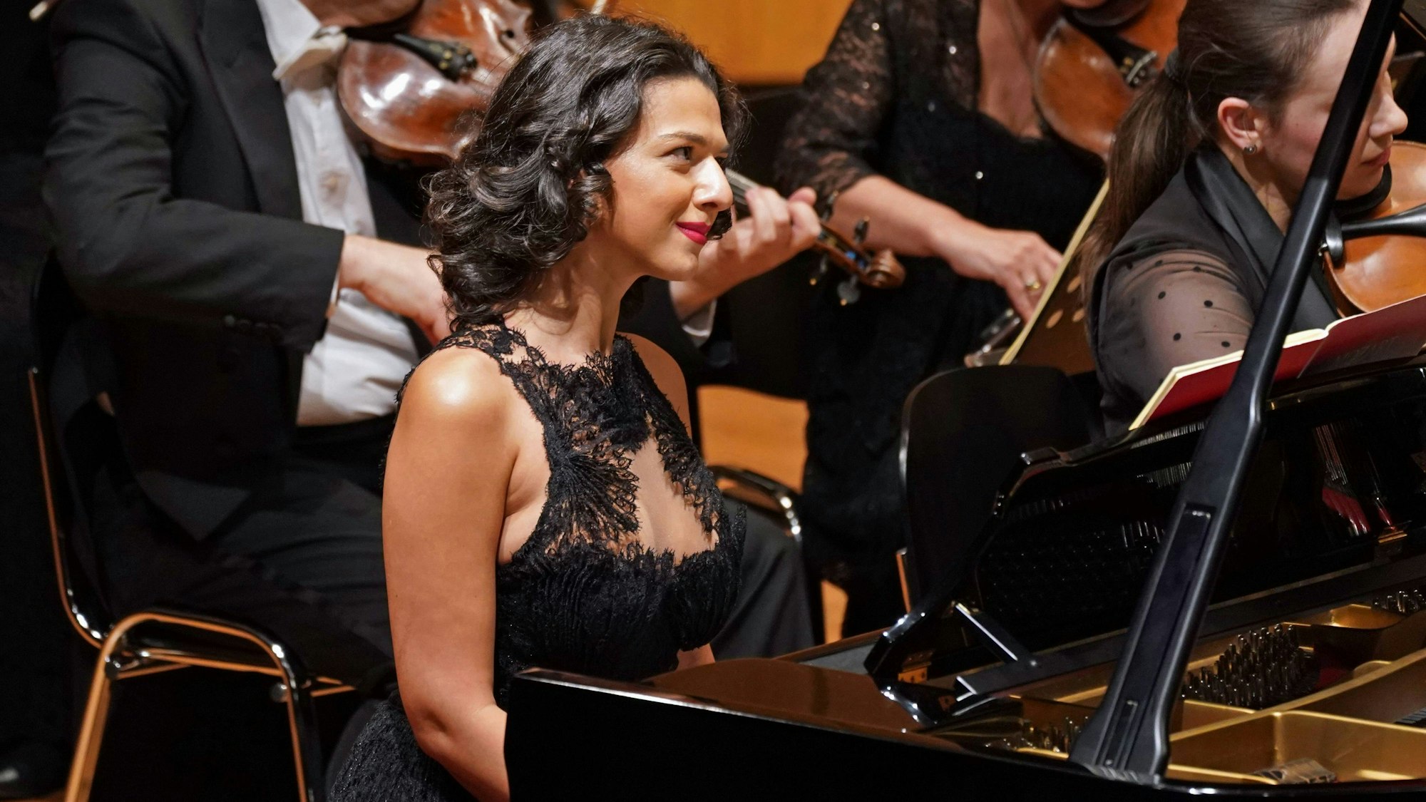 Pianistin Khatia Buniatishvili sitzt im Konzertsaal vor ihrem Flügel, sie hat dunkle Haare und trägt ein schwarzes Kleid.