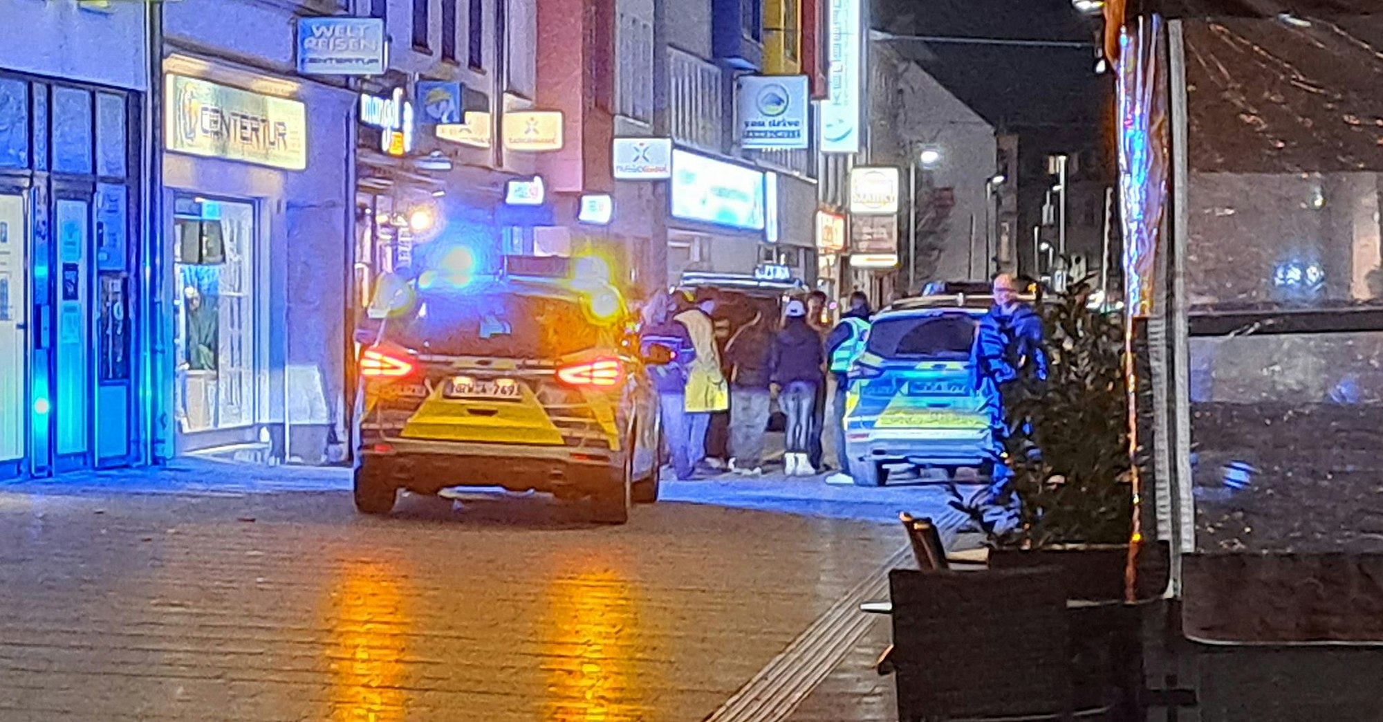 Polizeiautos stehen in einer Einkaufsstraße. Mehrere Personen stehen zwischen den Eisatzautos.