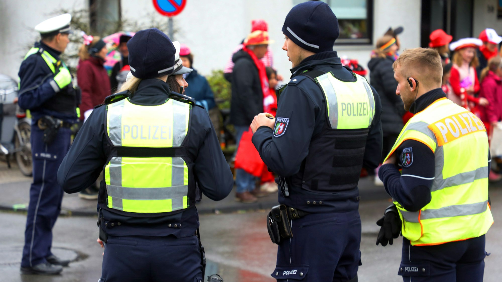 Polizisten stehen auf eine Straße und beobachten das Karnevalstreiben.