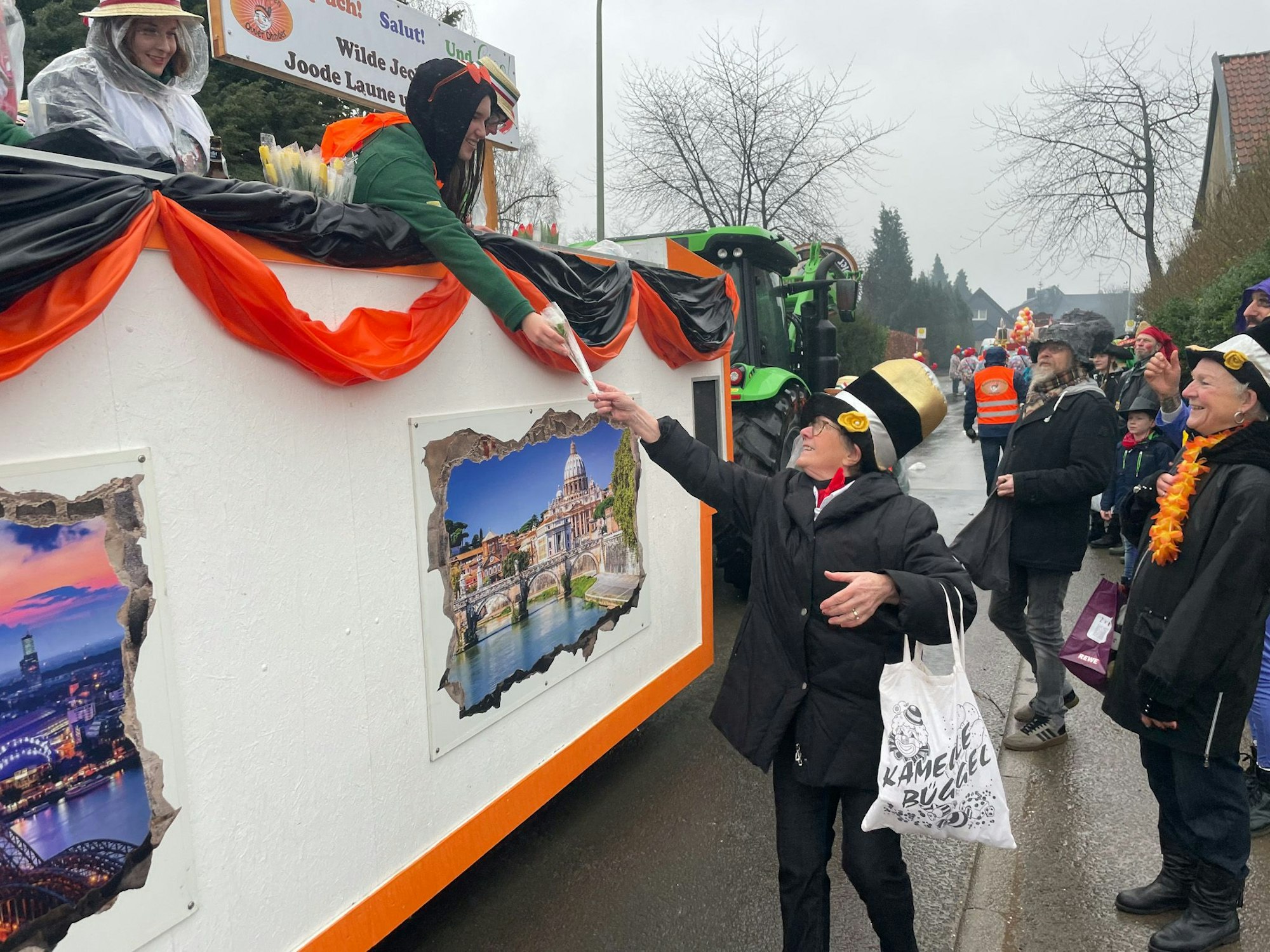 Eine Frau gibt einen Blumenstrauß von einem Karnevalswagen herunter.