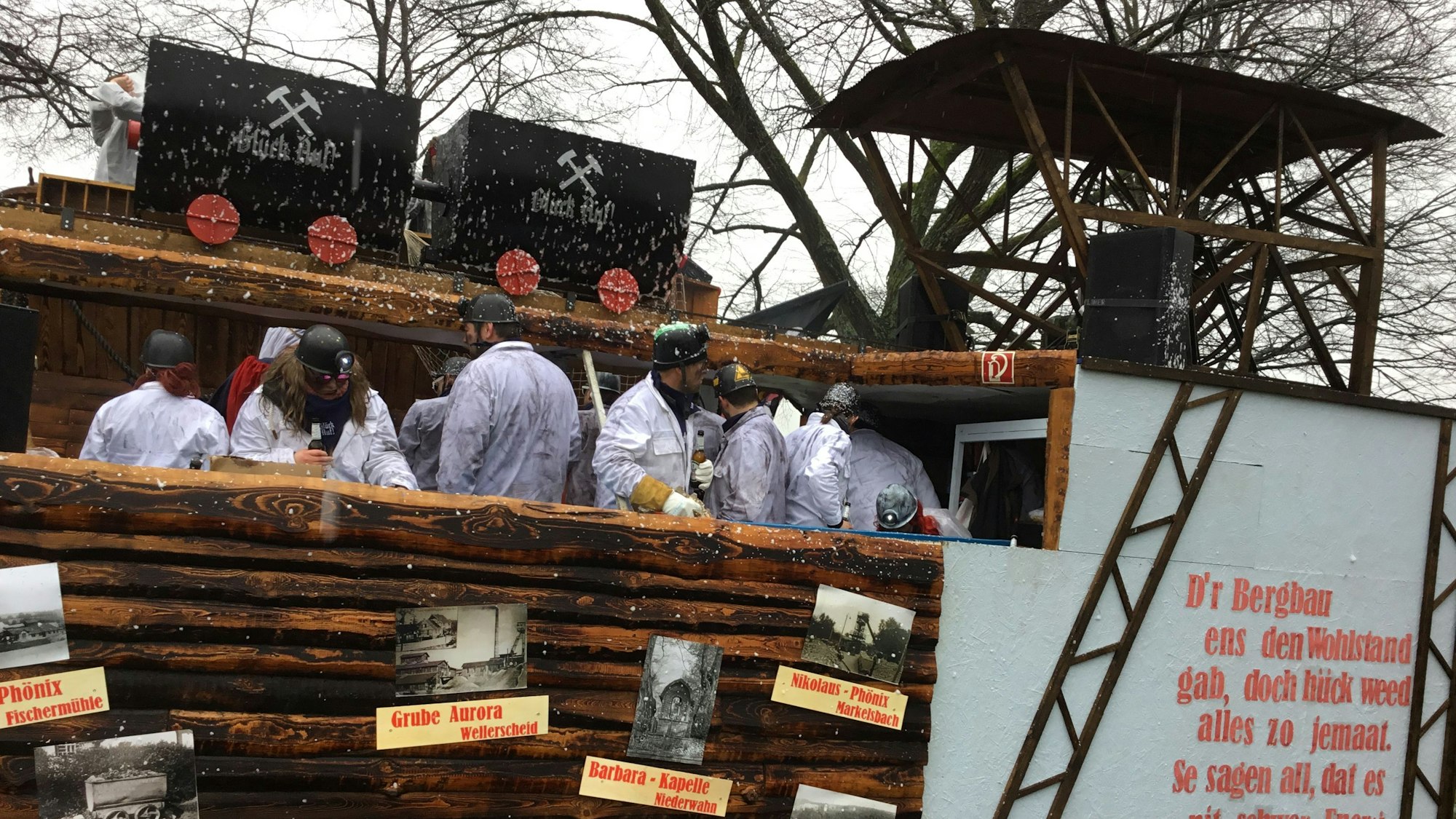 Eine weiß gekleidete Gruppe auf einem Karnevalswagen aus Holz.