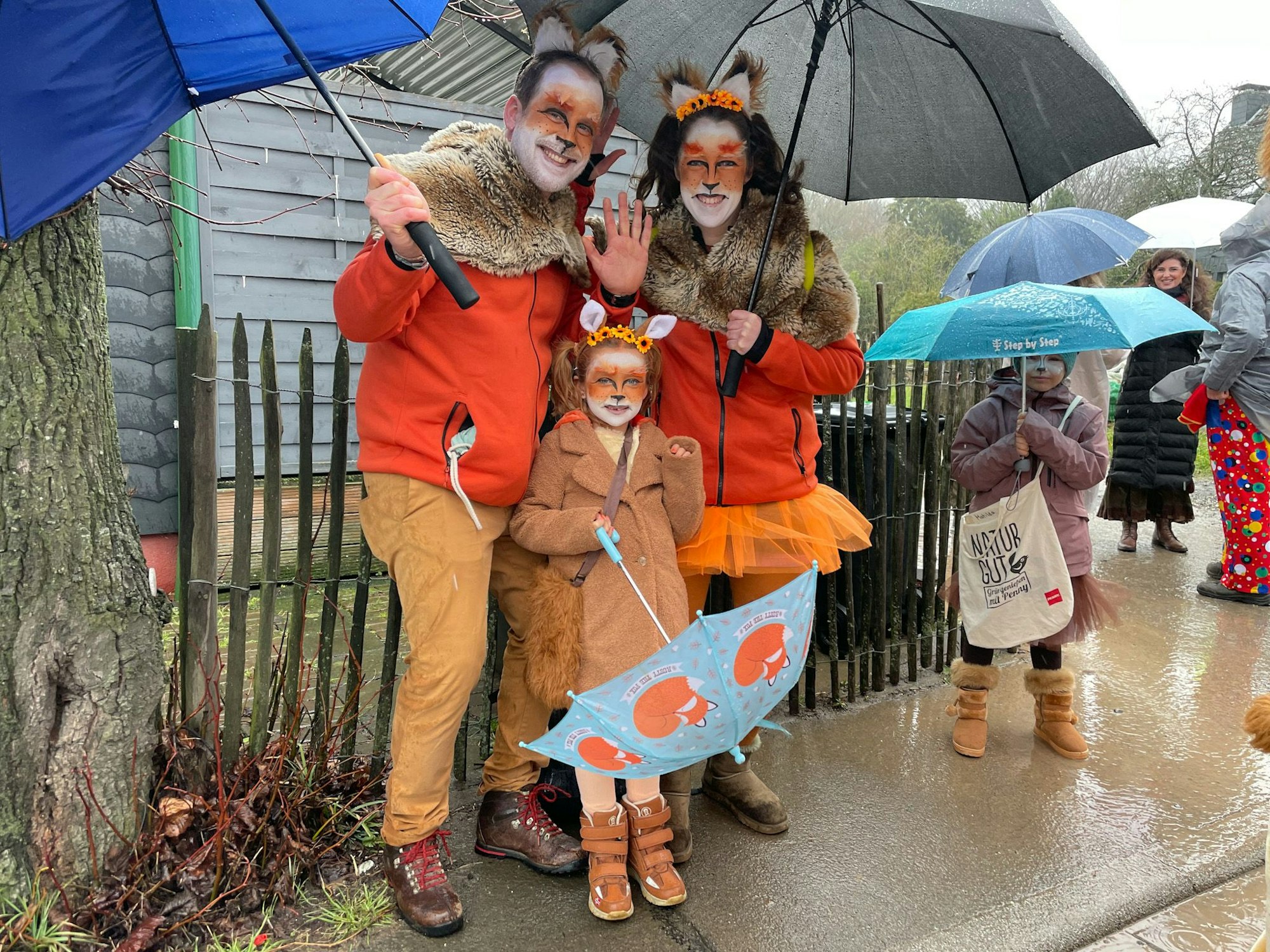 Dominic, Miriam und Milla (6) Hasenwinkel stehen als Tiere verkleidet und mit Regenschirmen am Zugrand.