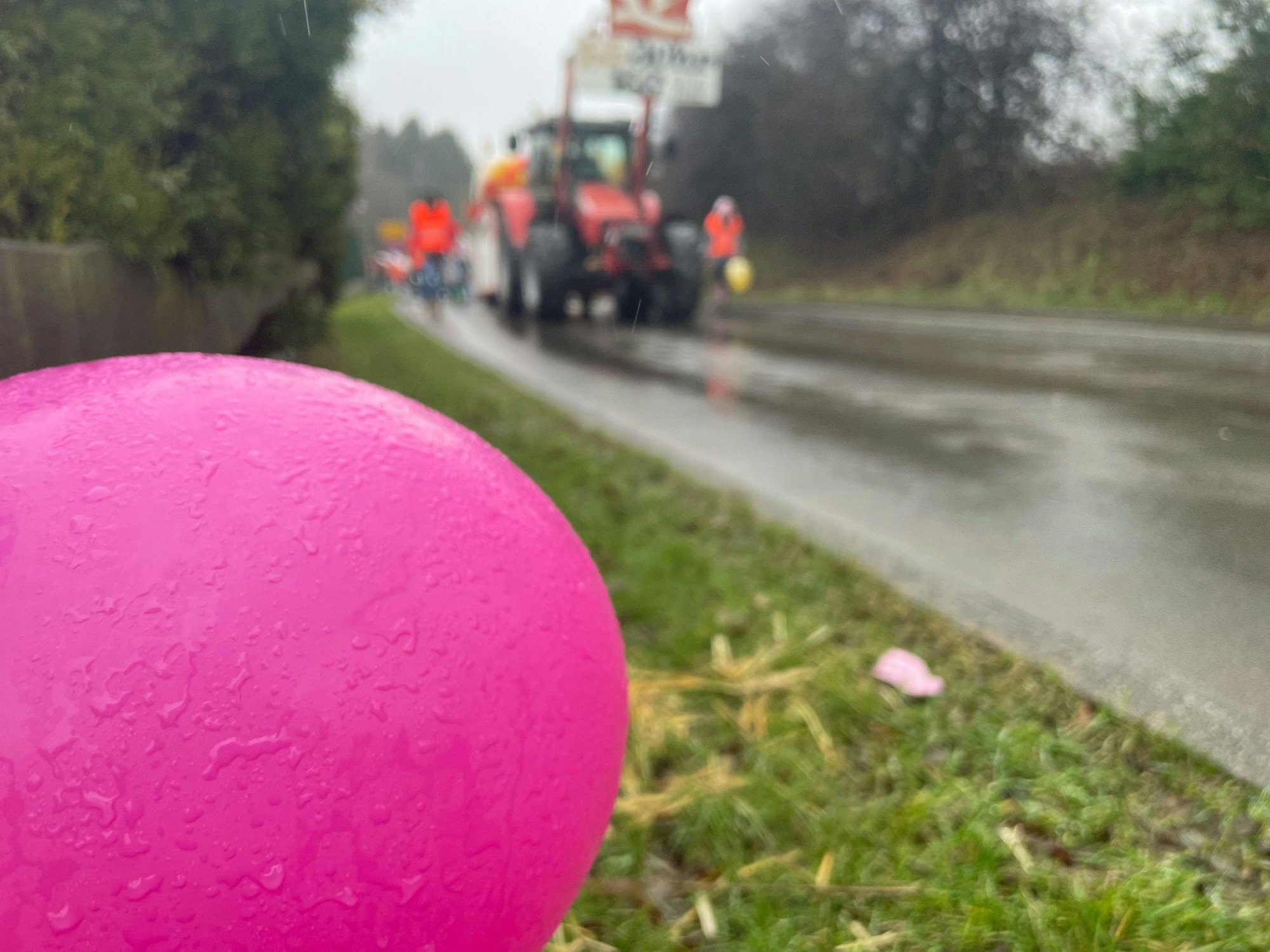 Ein nasser, pinker Luftballon weht im Vordergrund, im Hintergrund rollt der Zug heran.